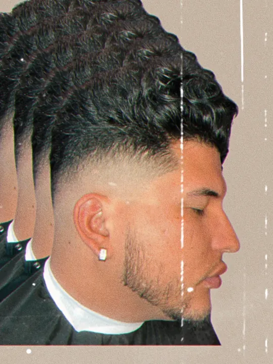 Curly top with a fade and a trimmed beard, side profile